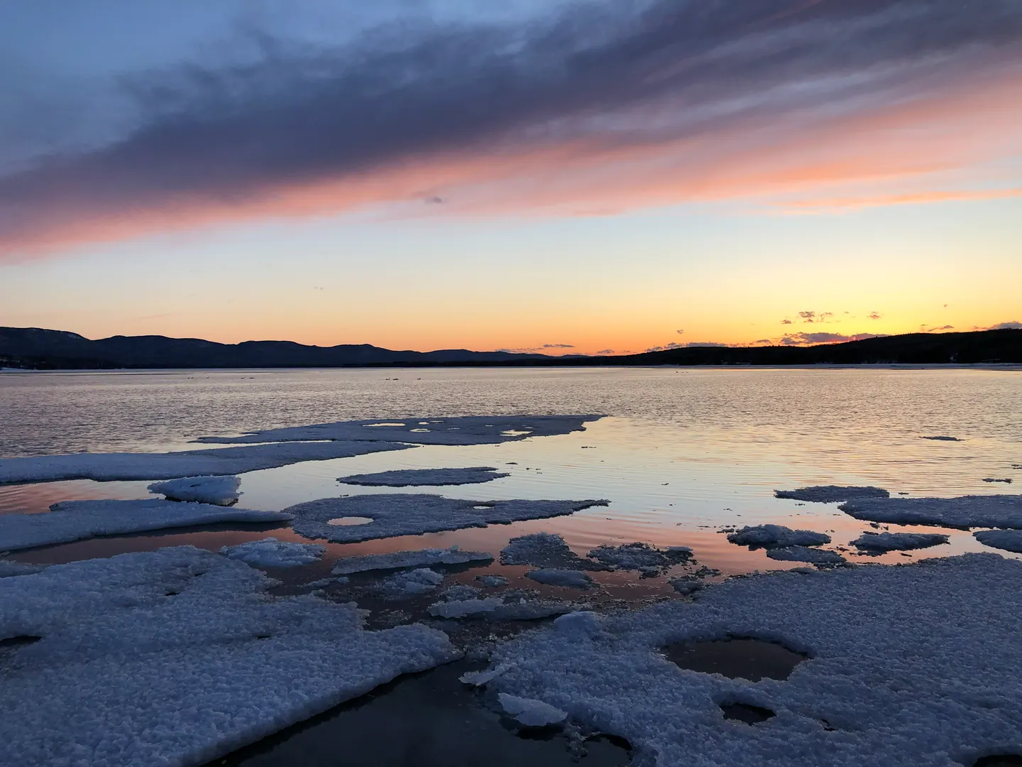 Banquise éclatée au coucher du soleil, ciel rose au-dessus de la baie